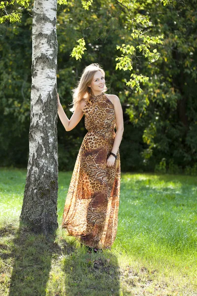 Beautiful blonde in leopard print long dress — Stock Photo, Image