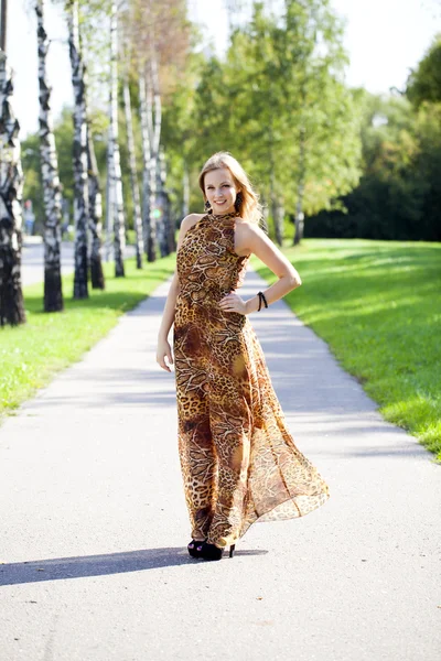 Mooie blonde in luipaard print lange jurk — Stockfoto