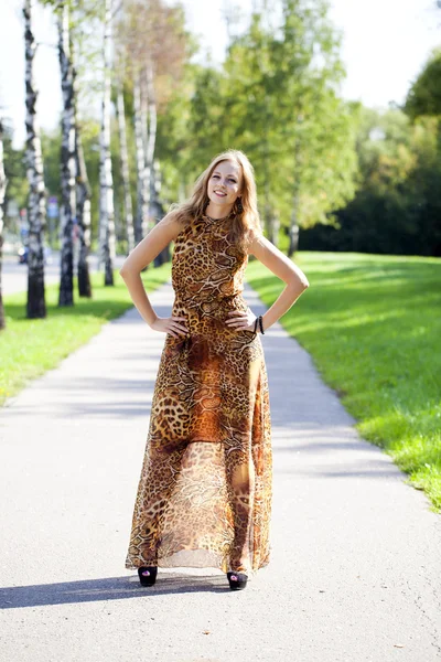 Mooie blonde in luipaard print lange jurk — Stockfoto