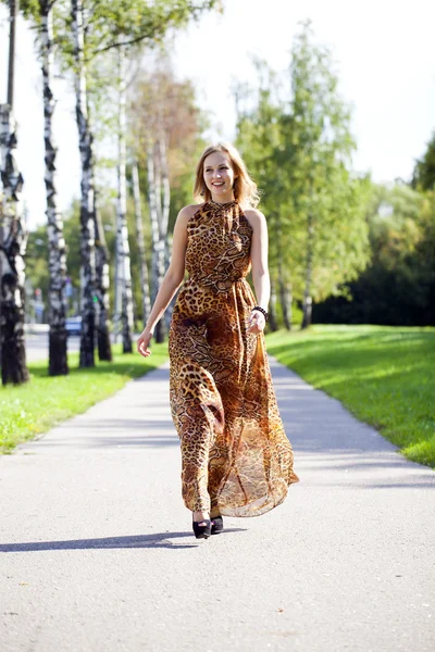 Beautiful blonde in leopard print long dress — Stock Photo, Image