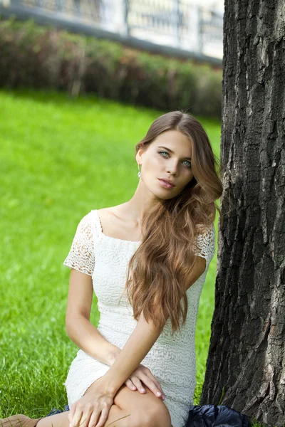 Yeşil çimenlerin üzerinde oturan genç güzel kız — Stok fotoğraf