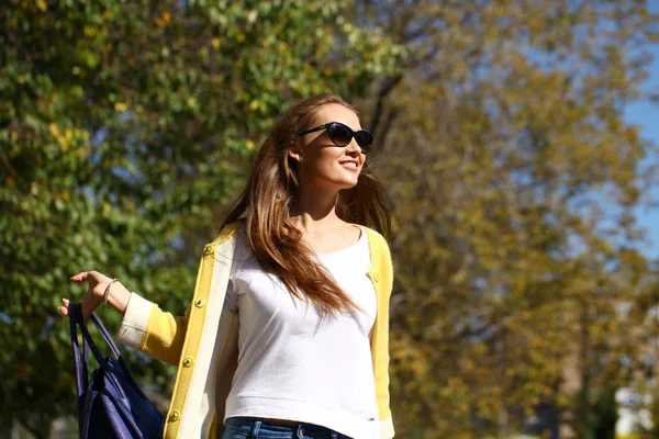 Mutlu bir kadın sarı montlu sonbahar street yürüyüş — Stok fotoğraf