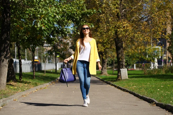 Happy woman in yellow coat walking autumn street — Stock Photo, Image