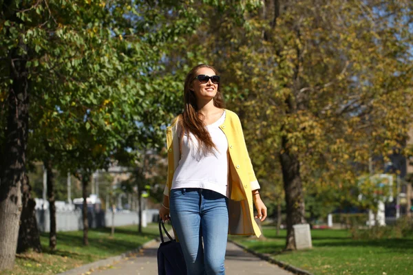 Happy woman in yellow coat walking autumn street — Stock Photo, Image