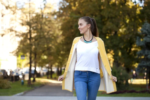 Mujer joven feliz en abrigo amarillo en la calle de otoño —  Fotos de Stock