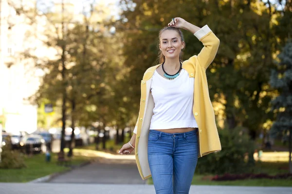 Mujer joven feliz en abrigo amarillo en la calle de otoño — Foto de Stock