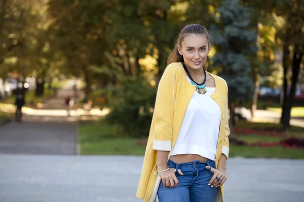 Mujer joven feliz en abrigo amarillo en la calle de otoño —  Fotos de Stock