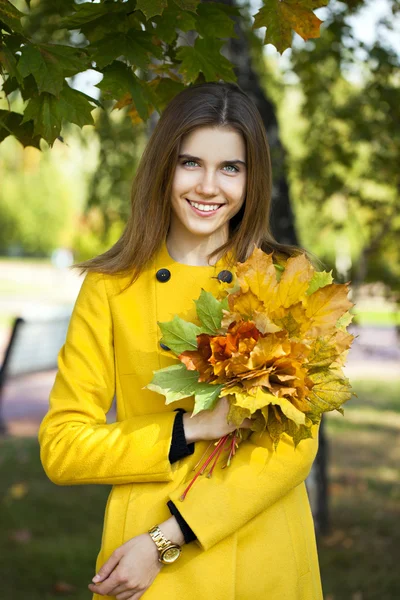 Boldog, fiatal nő, a sárga kabát, az őszi park — Stock Fotó