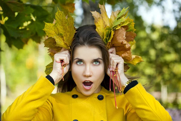 Happy young woman in yellow coat in autumn park — Stock Photo, Image