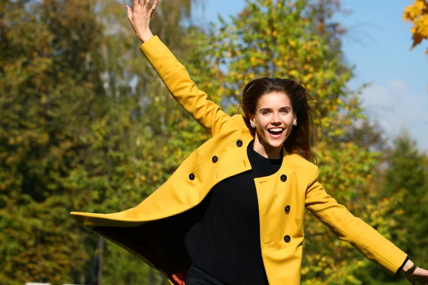 Mujer joven feliz en abrigo amarillo en la calle de otoño —  Fotos de Stock