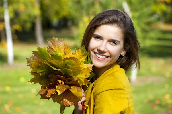 Mujer joven feliz en abrigo amarillo en el parque de otoño —  Fotos de Stock