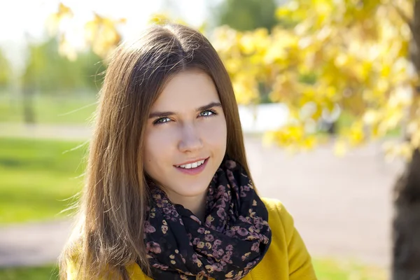 Happy young woman in yellow coat in autumn street — Stock Photo, Image