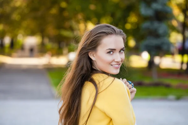 Glad ung kvinna i gul jacka på hösten gatan — Stockfoto