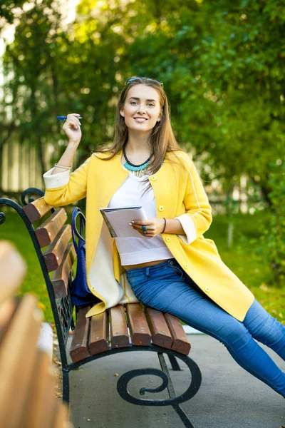 Schöne junge Frau im gelben Mantel — Stockfoto