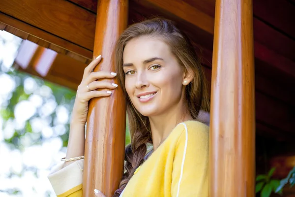 Glad ung kvinna som står på verandan i ett trähus — Stockfoto