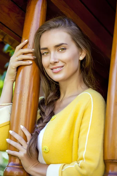 Happy young woman standing on the porch of a wooden house — Stock Photo, Image