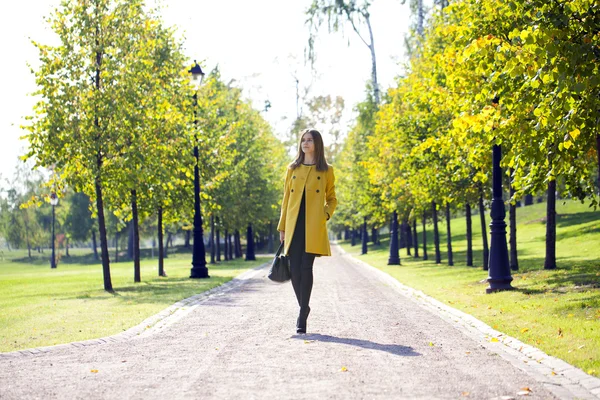 Mujer feliz en abrigo amarillo caminando calle otoño —  Fotos de Stock