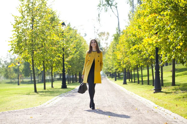 Mujer feliz en abrigo amarillo caminando calle otoño —  Fotos de Stock