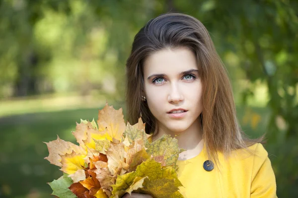 幸福的年轻女人，在黄色的外套，在秋天的公园 — 图库照片