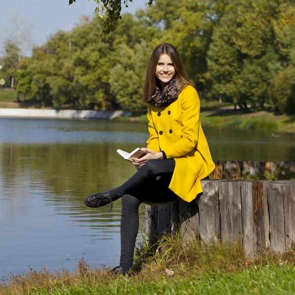 Beautiful young woman in yellow coat — Stock Photo, Image