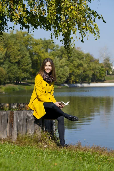 Beautiful young woman in yellow coat — Stock Photo, Image