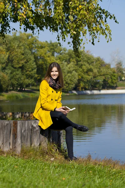 Beautiful young woman in yellow coat — Stock Photo, Image