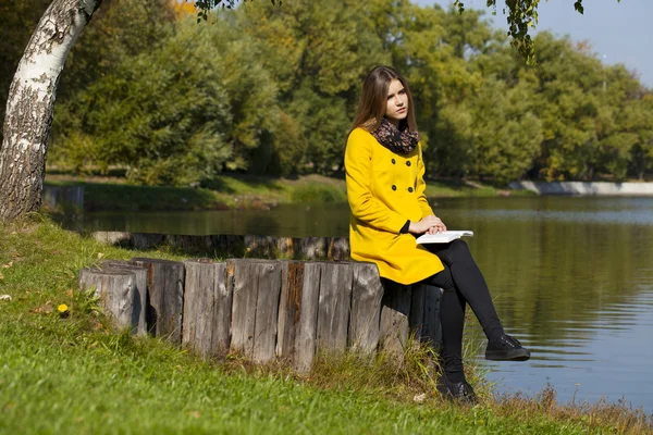 Beautiful young woman in yellow coat — Stock Photo, Image