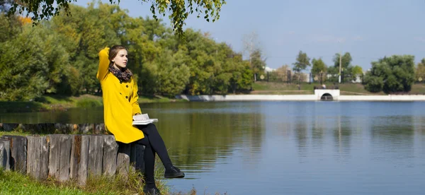 Mooie jonge vrouw in gele jas — Stockfoto