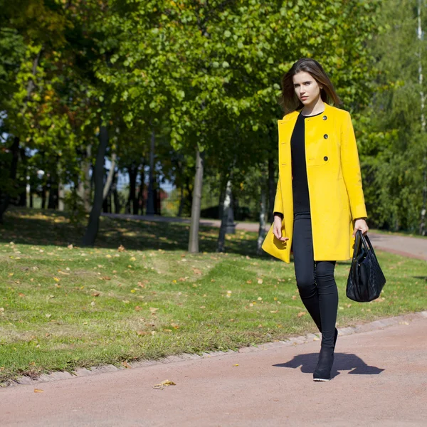 Gelukkig jonge vrouw in gele jas in het najaar straat — Stockfoto