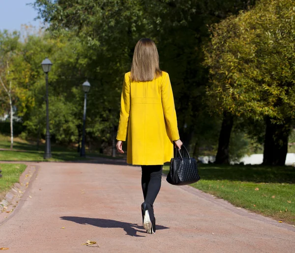 Gelukkig jonge vrouw in gele jas in het najaar straat — Stockfoto