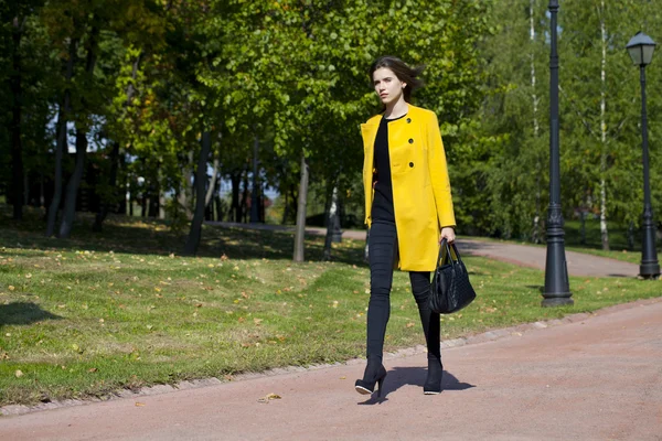 Mujer joven feliz en abrigo amarillo en la calle de otoño —  Fotos de Stock