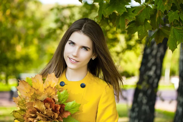 Happy young woman in yellow coat in autumn park — Stock Photo, Image