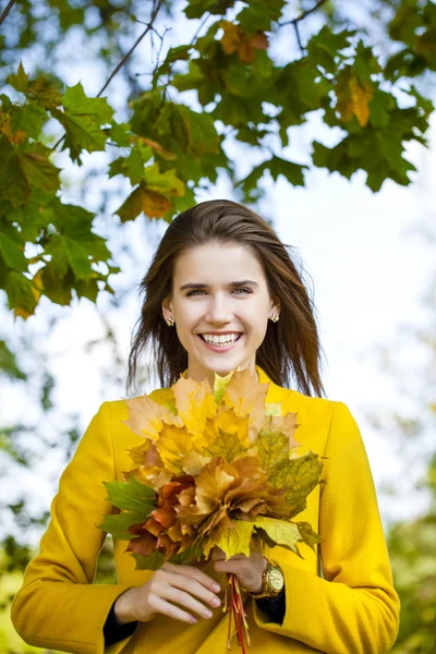 Glückliche junge Frau in gelbem Mantel im Herbstpark — Stockfoto