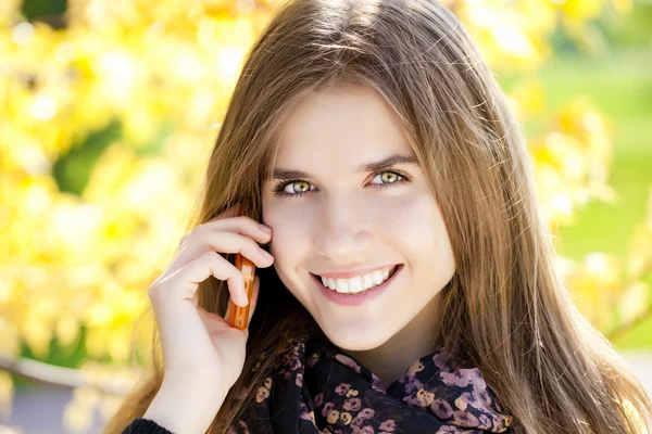 Happy beautiful woman calling by phone in autumn street — Stock Photo, Image