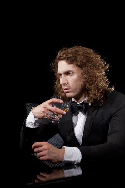 Eleganter junger Mann mit einem Glas Schnaps, der wegschaut — Stockfoto