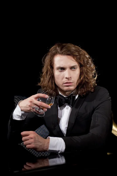 Elegantní mladý muž, který držel sklenici brandy koukal — Stock fotografie