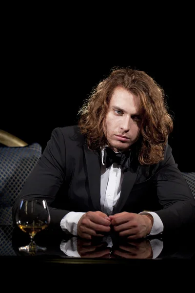 Elegant ung man med ett glas konjak tittar bort — Stockfoto