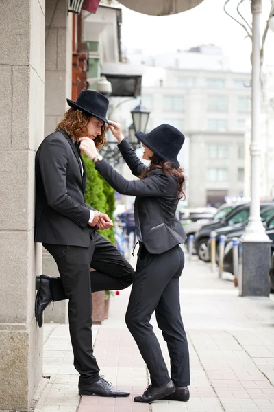 Молода щаслива стильна пара в чорних капелюхах позує на вулиці — стокове фото