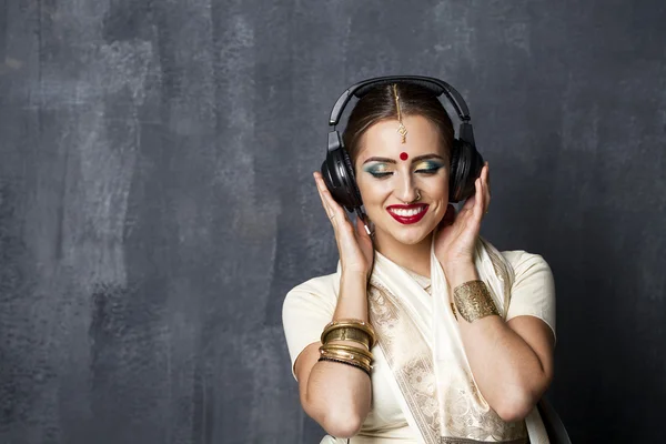 美しいインドの女性のヘッドフォンで音楽を聴く — ストック写真