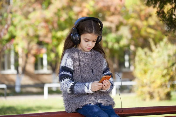 漂亮的小女孩在耳机上听音乐 — 图库照片