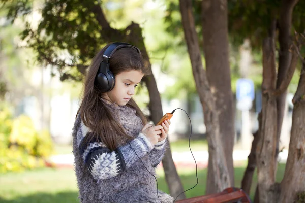 Belle petite fille écoutant de la musique sur écouteurs — Photo