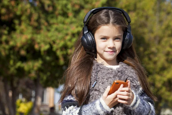 Belle petite fille écoutant de la musique sur écouteurs — Photo