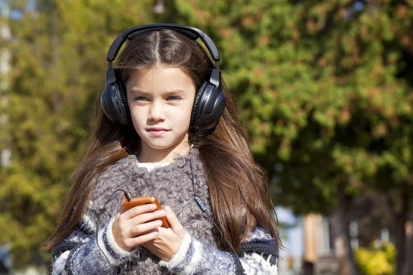 Belle petite fille écoutant de la musique sur écouteurs — Photo