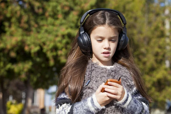 漂亮的小女孩在耳机上听音乐 — 图库照片