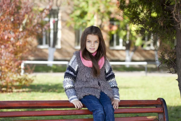 Vacker liten flicka satt på en bänk — Stockfoto