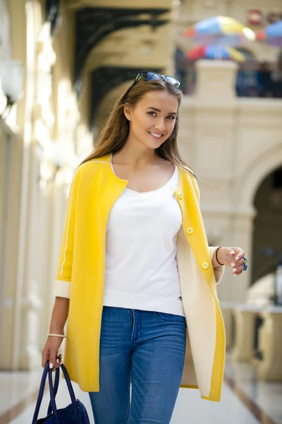 Молодая женщина в желтом пальто гуляет по магазину — стоковое фото