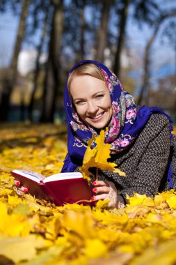 Güzel genç kız sonbahar üzerinde yalan ile kırmızı kitap yaprakları