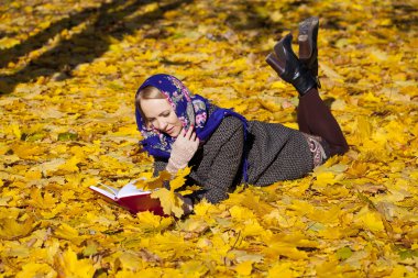 Güzel genç kız sonbahar üzerinde yalan ile kırmızı kitap yaprakları