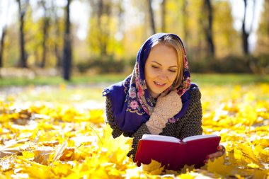 Güzel genç kız sonbahar üzerinde yalan ile kırmızı kitap yaprakları