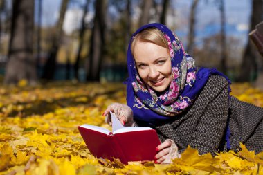 Güzel genç kız sonbahar üzerinde yalan ile kırmızı kitap yaprakları